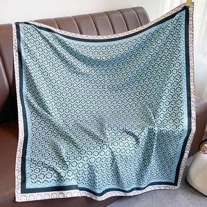 Dettaglio di un foulard di seta blu con motivo a catena su superficie in pelle