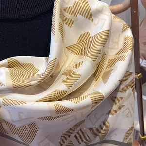 Macro view of twill satin scarf showing gold geometric patterns and silky texture