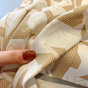 Close-up of premium twill silk scarf showing letter F print and satin texture detail