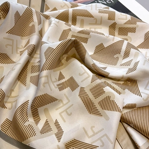 Detail of luxury silk scarf featuring champagne gold twill fabric and geometric patterns