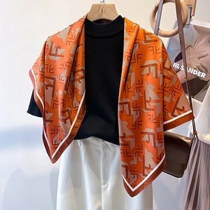 Fashionable orange geometric silk scarf paired with a white suit for an elegant autumn look