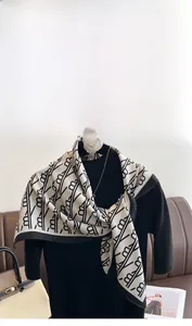 Détail d'un carré de soie en sergé avec imprimé lettres noir et blanc et broche camélia
