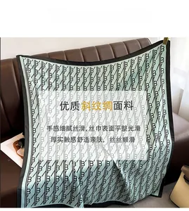 Détail du foulard en soie sergé vert clair avec motif monogramme noir et bordure large