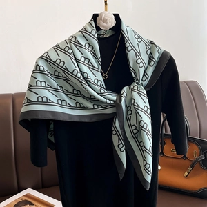 Détail d'un foulard en soie bleu clair avec rayures noires en B sur un mannequin