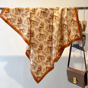 Detailed close-up of a geometric print twill square scarf with caramel orange border