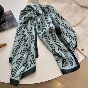 Foulard en soie bleu clair avec motifs de branches noires sur veste en tweed blanche