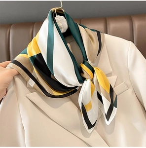 Detail of silk-like square scarf tied on beige blazer with geometric color block patterns