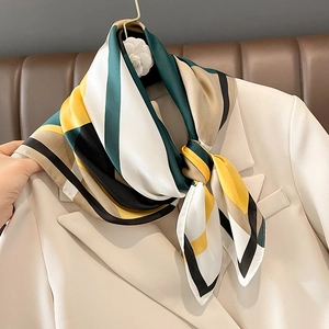 Silky geometric striped scarf in emerald and gold styled on a beige blazer collar
