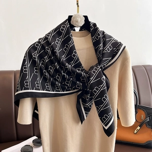 Carré de soie à motif géométrique noir et blanc sur un haut en maille beige