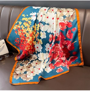 Détail d'un foulard en soie à imprimé floral drapé sur un canapé en cuir avec fleurs