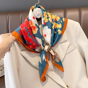 Foulard en soie à imprimé floral bleu canard et orange sur un blazer blanc