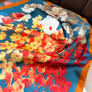 Gros plan d'un foulard en soie à imprimé floral abstrait orange et bleu satiné vibrant