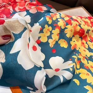 Détail d'un foulard en soie avec imprimé floral et bords roulottés à la main orange vif