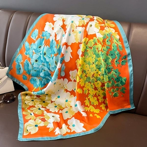Gros plan du motif floral sur une écharpe en satin drapée sur un canapé en cuir