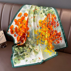 Carré de soie satinée à imprimé floral drapé élégamment sur un fauteuil en cuir marron