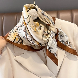 Eleganter Magnolien-Seidenschal in Beige mit braunem Rand an einem Anzugsrevers