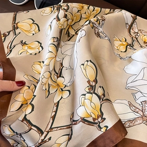 Detailansicht eines Seidenschals mit Magnolienprint und braunem Kontrastrand