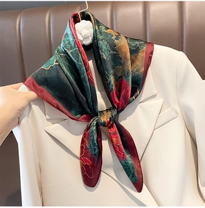Detailed view of a floral silk square scarf styled with a white professional blazer