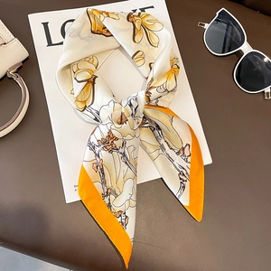Eleganter Magnolien-Seidenschal mit orangefarbenem Rand auf einem Modemagazin