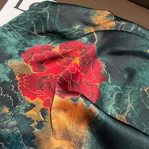 Detailed macro view of luxurious silk scarf featuring red peonies and gold accents