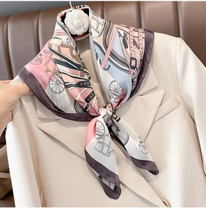 Detail of silk-like scarf with carriage pattern styled on a blazer with camellia brooch
