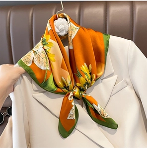 Close-up of silk scarf with yellow sunflowers on orange background tied to a suit
