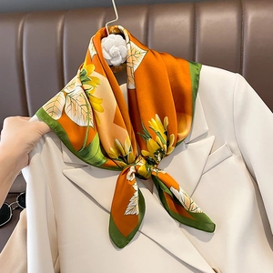 Fashionable silk-like square scarf with orange sunflower print on a white suit lapel