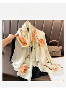 Detail of floral silk scarf with orange roses on cream fabric draped over a black outfit