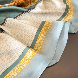 Détail de la texture du foulard en satin de soie montrant des motifs floraux et le tissu