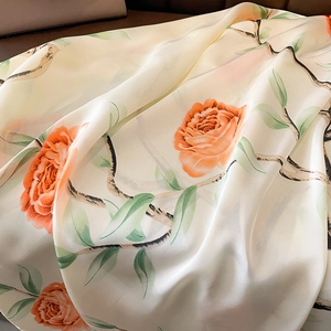 Macro detail of creamy white silk scarf with orange floral print and satin texture