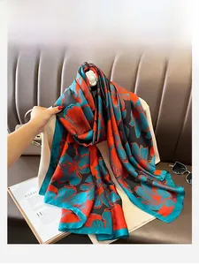 Detail eines Seidenschals mit Blumenmuster in Orange und Blau auf schwarzem Satin