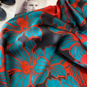 Detail eines Seidenschals mit Blumenmuster neben Sonnenbrille und Magazin