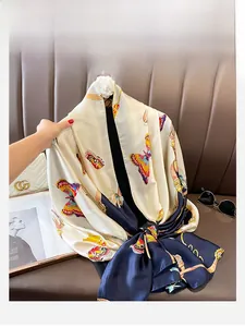 Detail of silk-like scarf featuring beige and navy color block with butterfly patterns