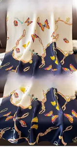 Detailed view of navy silk scarf featuring butterfly and chain prints with premium hem