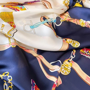 Close-up detail of luxurious silk scarf showing butterfly and equestrian chain patterns