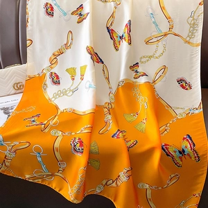 Detail of luxury silk scarf featuring butterfly patterns and golden chain strap motifs