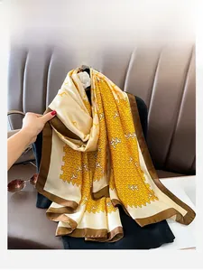 Détail d'un foulard en soie à motif géométrique élégant en jaune gingembre et crème satinée