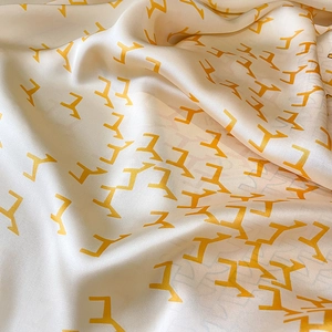 Gros plan détaillé d'une écharpe en soie beige avec motifs géométriques orange élégants