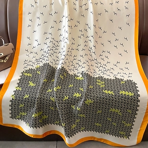 Détail d'un foulard élégant en soie avec bordure orange posé sur un canapé en cuir