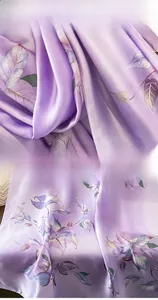Gros plan d'un foulard en soie violette avec motifs de feuilles et détails de couture