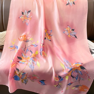 Gros plan d'un foulard en soie rose avec motifs floraux drapé sur une chaise en cuir