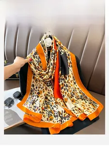 Detail of leopard print silk scarf with orange borders draped over a black blazer jacket