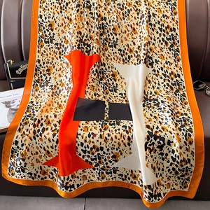 Detail of elegant leopard print silk scarf with orange borders on leather background