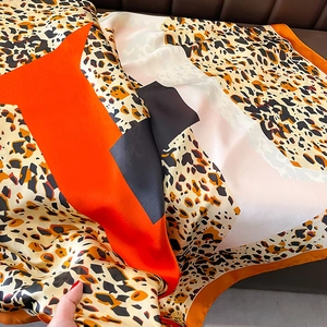Detailed close-up of leopard print silk scarf featuring bold orange and black color blocks