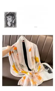 Detail of soft pink silk scarf featuring colorful oriental landscape print on leather sofa