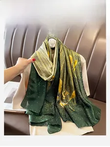 Détail d'un foulard en satin fin avec rayures vertes et dorées et motifs étoilés