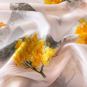 Detailed close-up of smooth silk scarf fabric with yellow floral ginkgo leaf pattern