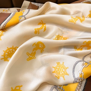 Close-up of silk scarf with nautical anchor and chain patterns on creamy satin fabric