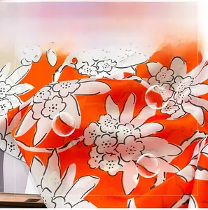 Macro detail of soft orange floral silk scarf showing delicate texture and fabric folds