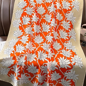 Detail of vibrant orange floral print scarf elegantly draped on a leather sofa